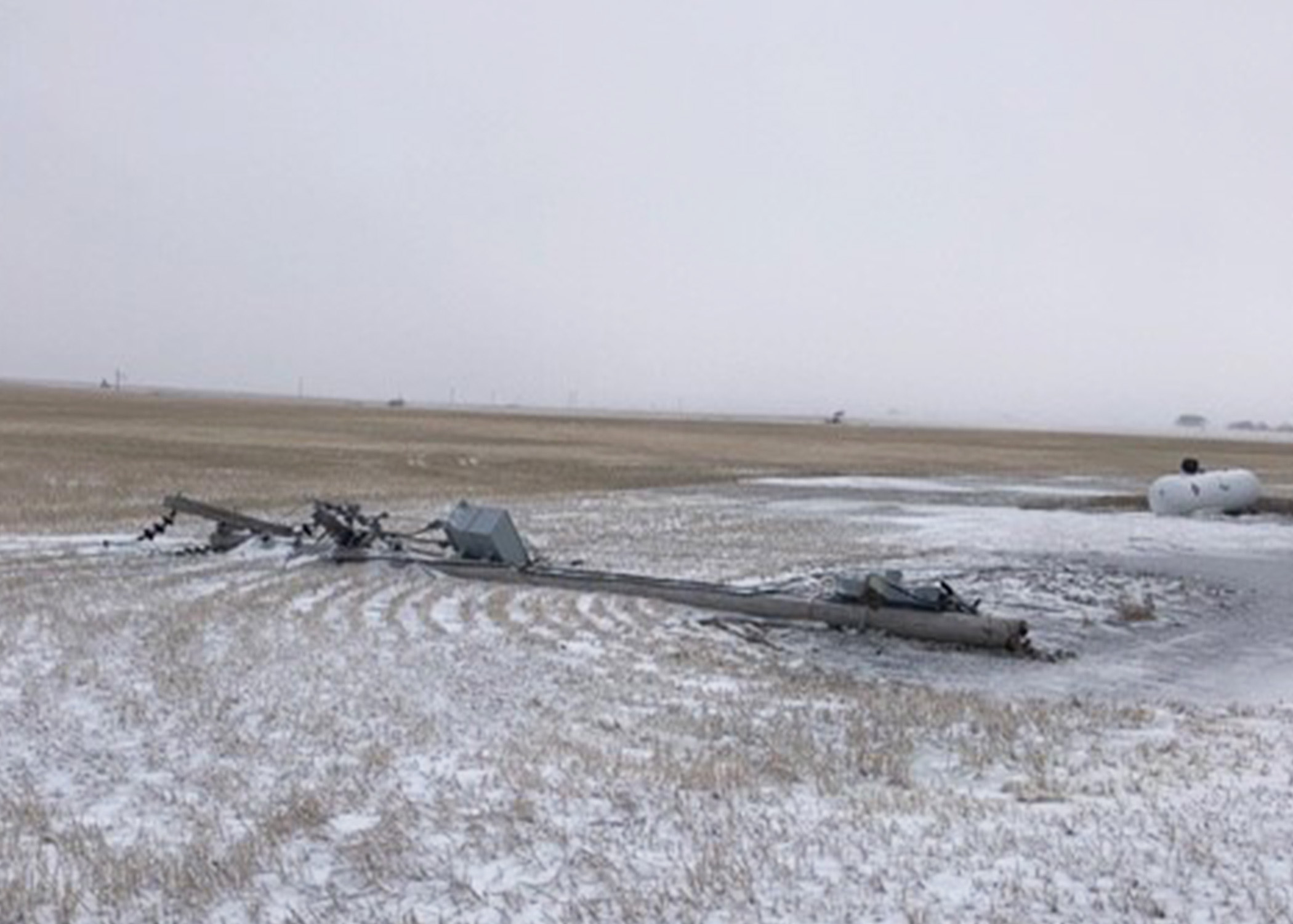 Power pole laying on a prairie field