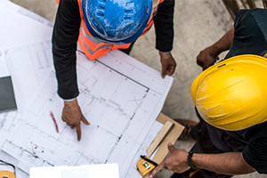 individuals with hard hats looking at a building plan