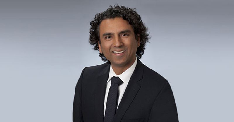 Rupen Pandya smiling wearing a black suit.