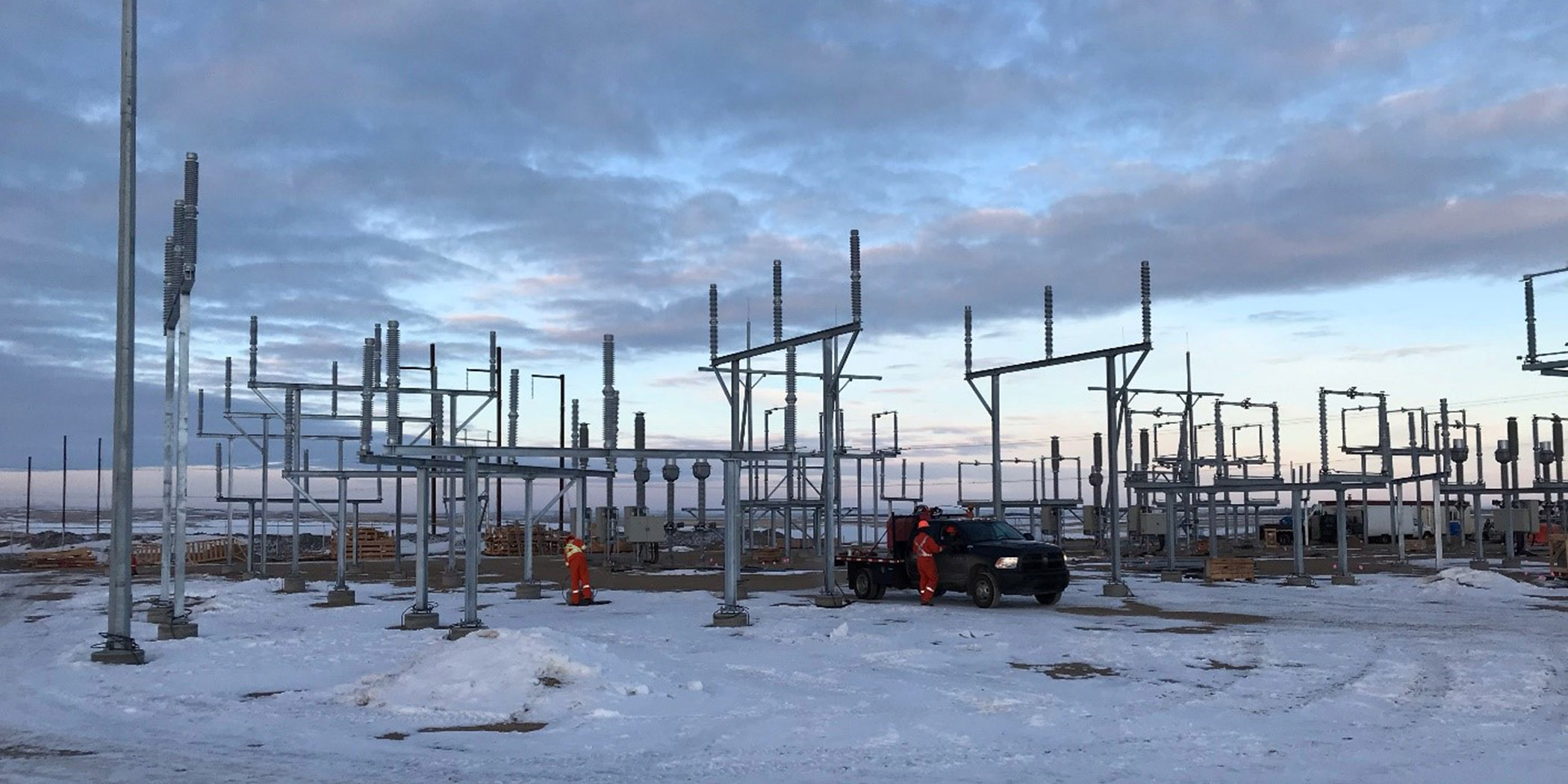 2 workers dressed in orange amongst a newly constructed substation