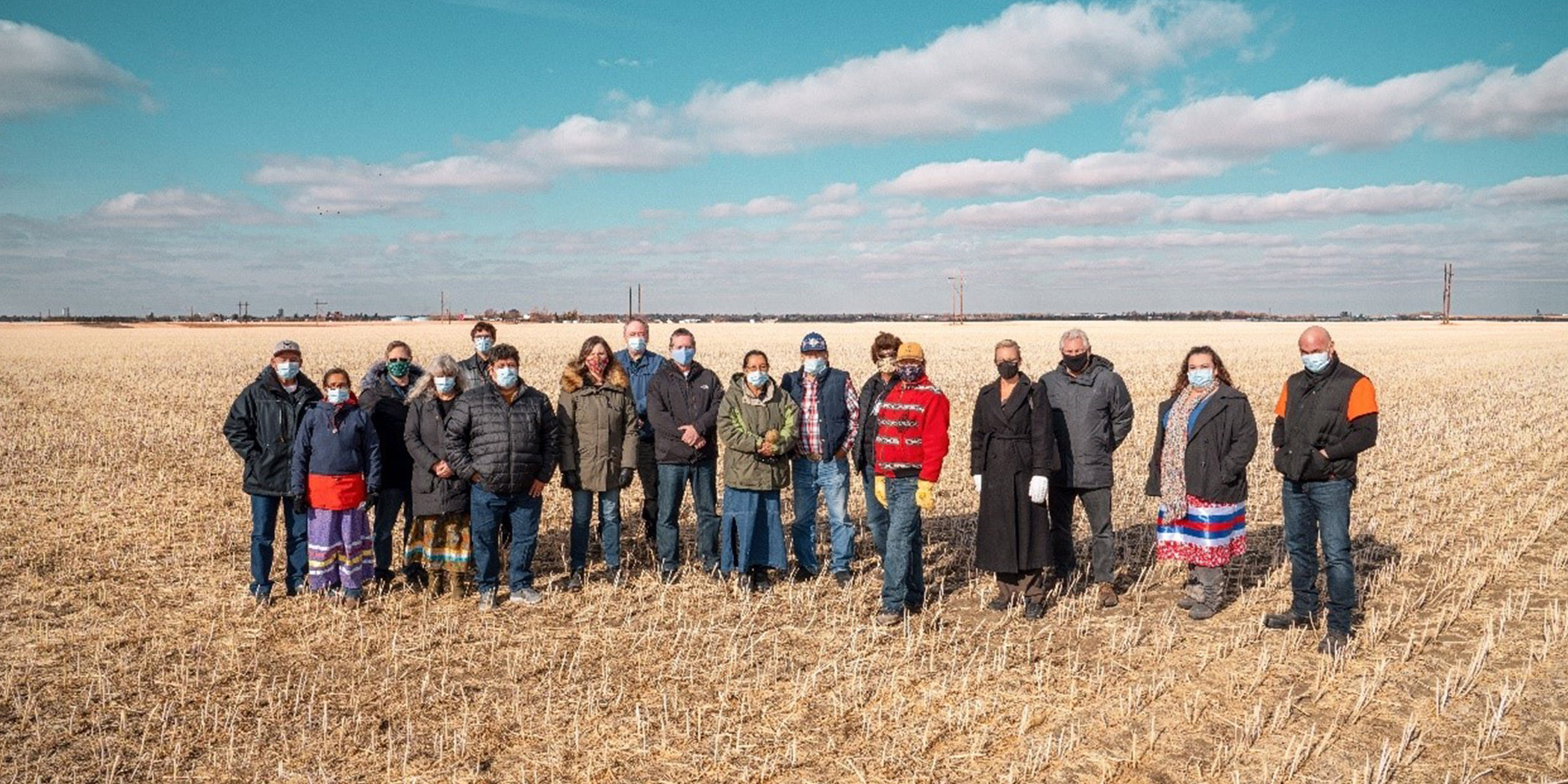 group of people standing in a field with blue sky in background